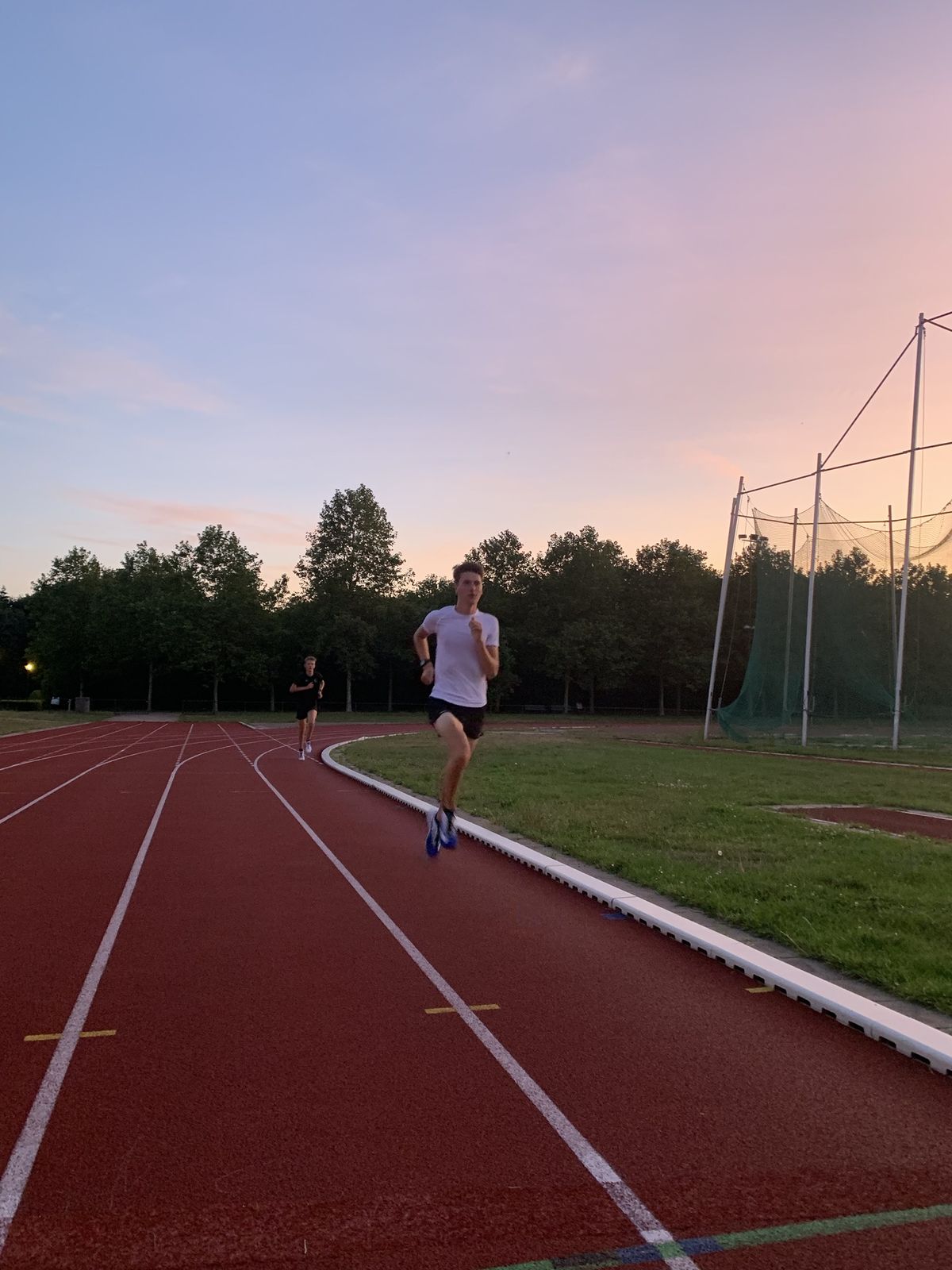 Loper op de atletiekbaan bij zonsondergang